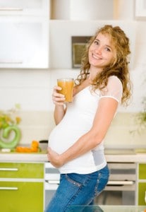donna incinta che beve un bicchiere di spremuta